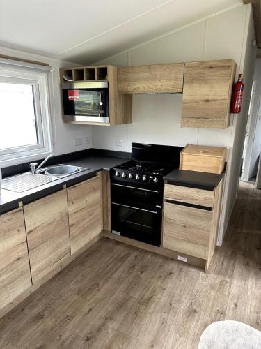 a kitchen with a stove and a sink at Luxury static caravan on SunnySands with mountain views in Barmouth