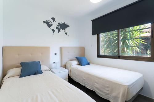 two beds in a room with a world map on the wall at Apartamentos Romandie by Saratur in San Bartolomé de Tirajana
