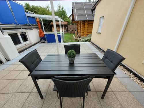a black table with chairs and a potted plant on a patio at Carpe Diem Wellness Ferienwohnung in Illingen