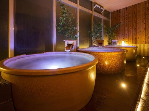 a bathroom with three large tubs with plants in it at Isaribinoyado Seaside Kancho in Wakayama