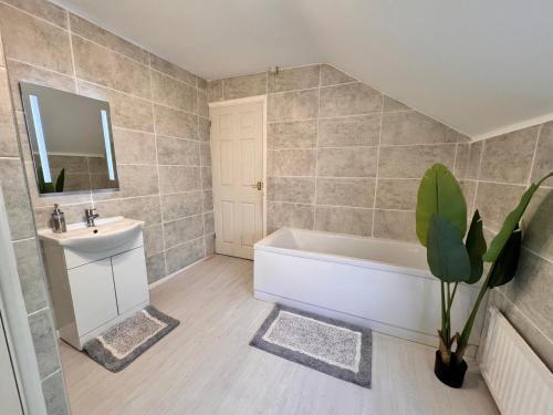 a bathroom with a white tub and a sink at Best Deal 1 Bed Apartment 5 minutes from Bedford in Bedford