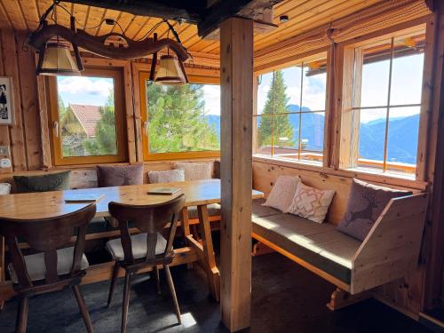 a dining room with a table and chairs and windows at Almhütte Enzian in Greifenburg