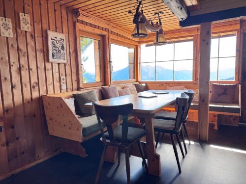 a dining room with a table and chairs and windows at Almhütte Enzian in Greifenburg