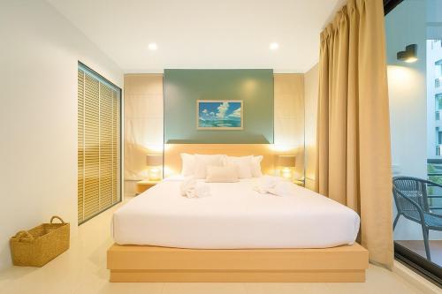 カマラビーチにあるKamalaya Hillside Sanctuary Kamala Beachの白いベッドと窓のある寝室