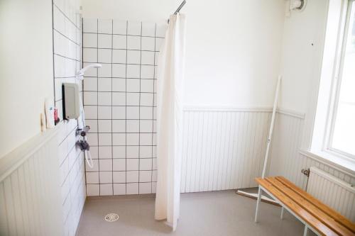 y baño con ducha y banco. en Stiftsgården Hostel Skellefteå, en Skellefteå