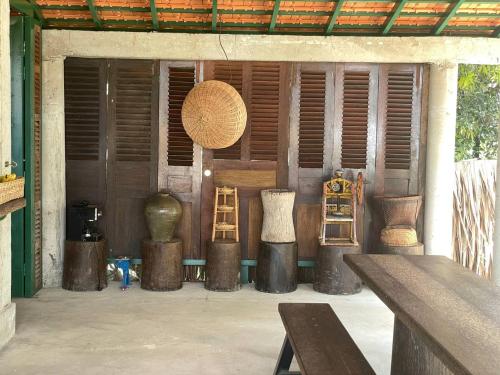 a group of vases and wooden tables in a room at Mlis Kampot River in Kampot