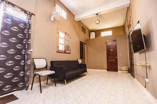 a living room with a black couch and a tv at Petit Havre de paix avec jardin - Centre Ville in Diego Suarez