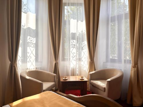 a bedroom with two chairs and a bed and windows at Vila Černý leknín in Tábor
