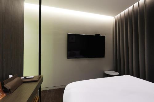 a hotel room with a bed and a flat screen tv at Pangyo Business & Tourist Hotel KYND in Seongnam