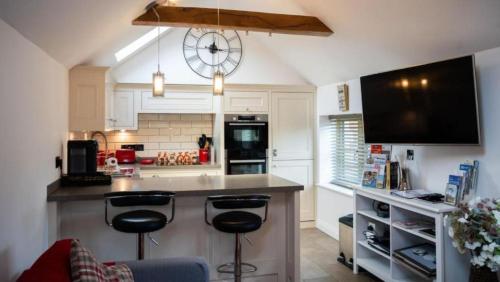 a kitchen with two bar stools and a clock on the wall at Modern 1-Bedroom Apartment in Holt in Holt