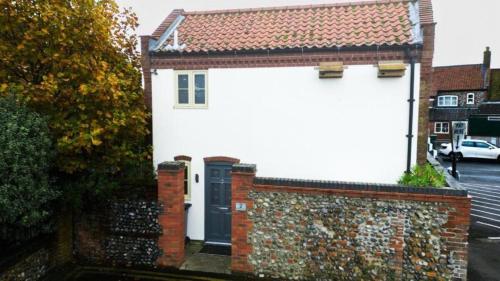 a white house with a black door and a brick wall at Modern 1-Bedroom Apartment in Holt in Holt
