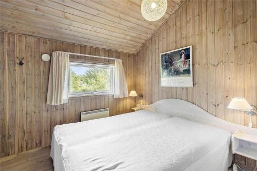 a bedroom with a white bed and a window at 1431-Aakirkeby-Strandvangen-13-B in Vester Sømarken