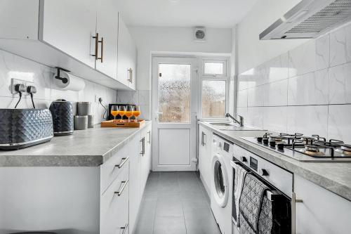 a white kitchen with a stove and a sink at 7 Beds, 4 Bedrooms, Parking, Close to Station in Parkside