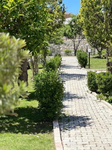 a brick walkway with bushes and trees in a park at Casa De Levıssı Ölüdeniz in Oludeniz