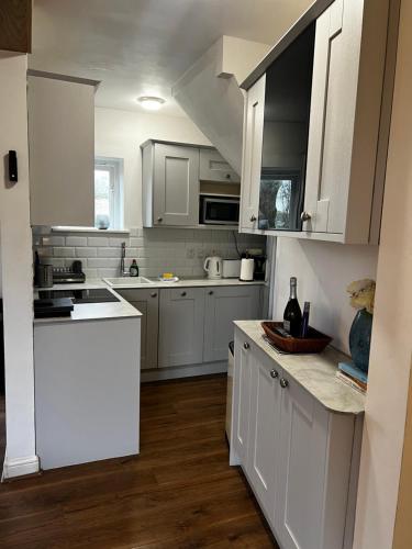eine weiße Küche mit weißen Schränken und einer Arbeitsplatte in der Unterkunft Castleford Cottage , Lowermill Estate in Somerford Keynes
