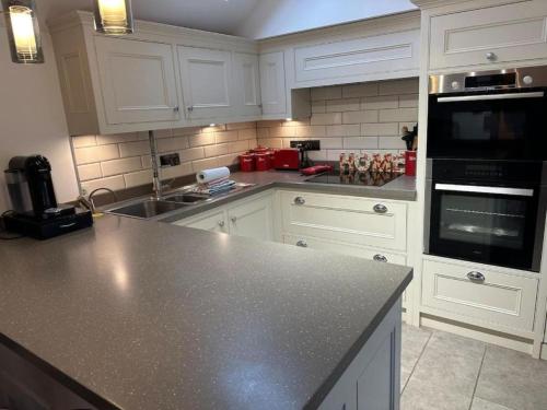 a kitchen with white cabinets and a black counter top at Modern 1-Bedroom Apartment in Holt in Holt