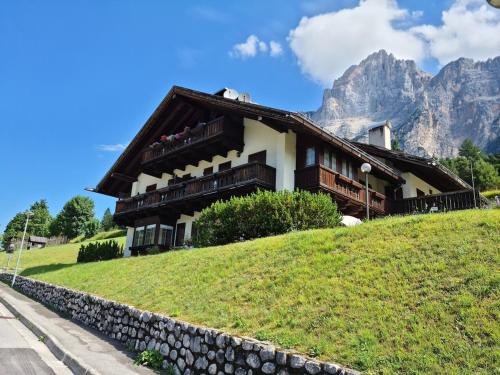 a house on a hill with mountains in the background at La Casa della Nonna in San Vito di Cadore