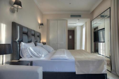 a bedroom with a large white bed and a television at Hotel Moskva in Budva
