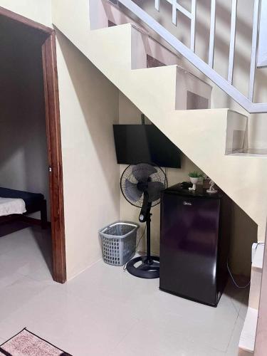 a room with a television and a desk under stairs at Ace Transient in Puerto Princesa City