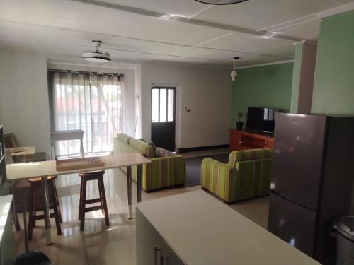 cocina y sala de estar con nevera y sillas en Puravida guesthouse, en Umkomaas
