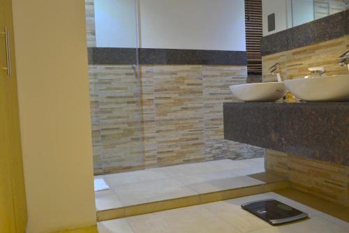 a bathroom with two sinks and a glass shower at La Maison Royale in Nairobi