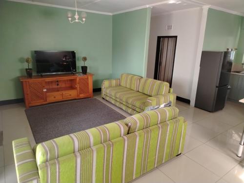 Una sala de estar con dos sofás y un televisor. en Puravida guesthouse, en Umkomaas