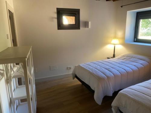 a bedroom with two beds and a table and a window at El Molino del Burgo de Osma in El Burgo de Osma