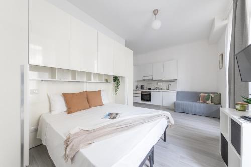 a white bedroom with a large bed and a kitchen at Magic Rent - Appartamento Gluck in Milan