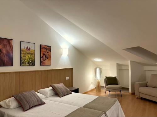 a bedroom with a bed and a couch and a chair at Hotel Rural El Majuelo in Montorio