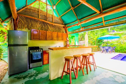 a kitchen with a bar with stools in it at Aloha Surf Nosara - Kahala Hui Cabins #3 in Nosara