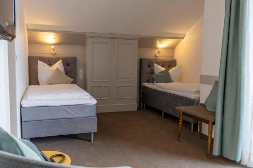 a room with two beds and a chair in it at Hotel Lindenhof Hubmersberg in Pommelsbrunn