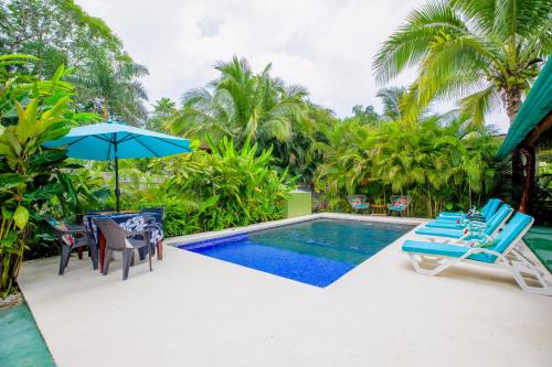 a swimming pool with chairs and an umbrella at Aloha Surf Nosara - Kahala Hui Cabins #3 in Nosara