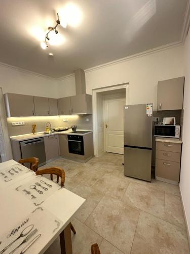 a kitchen with a table and a refrigerator at Noémi Apartman Újfehértó in Újfehértó