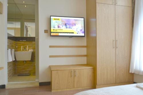 a room with a tv on a wall with a bathroom at La Maison Royale in Nairobi