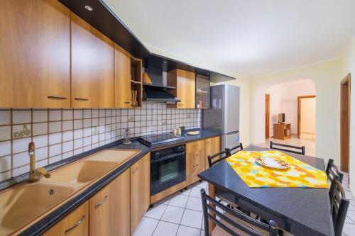 eine Küche mit Holzschränken, einer Spüle und einem Tisch in der Unterkunft Casa vacanze Casalena 