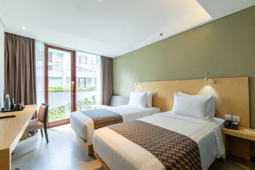 a hotel room with two beds and a window at Episode Kuta Bali in Kuta