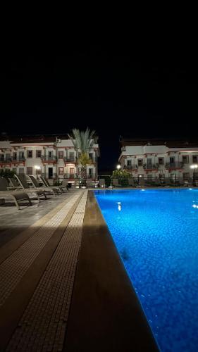 a swimming pool at night with chairs and buildings at Casa De Levıssı Ölüdeniz in Oludeniz