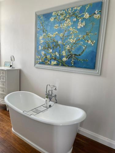 a white bath tub in a bathroom with a painting at Chateau de Minargent in Aulnay
