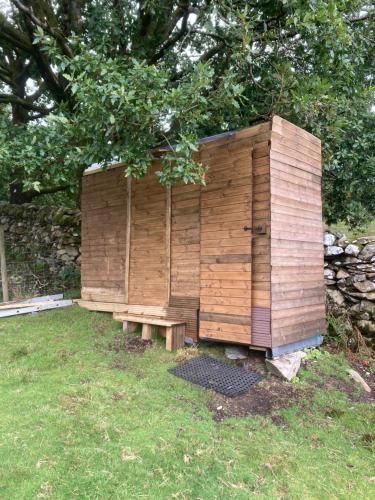a wooden out house with a bench in the grass at Shepherds Hut on Alpaca and working farm in Blaenau-Ffestiniog