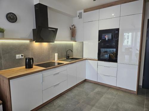 a kitchen with white cabinets and a sink and a microwave at Apartament Onkologia Politechnika ul Akademicka 8A in Bydgoszcz