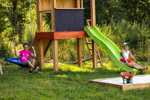 two girls sitting on a slide in a playground at Le Galussel Gite d'étape et de séjour in Saint-Sébastien
