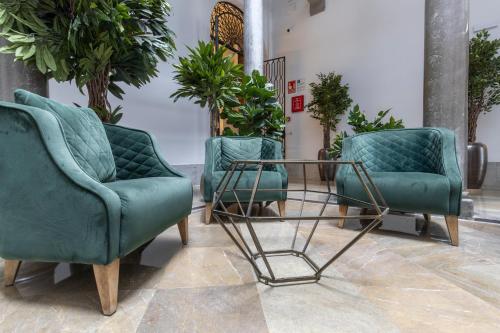 two chairs and a table in a room with plants at BiBo Suites Palacio de Portago in Granada