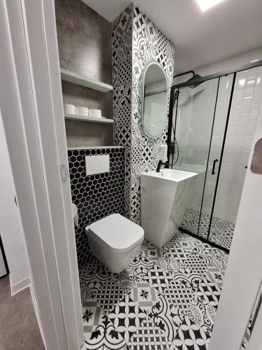 Baño en blanco y negro con aseo y lavamanos en Ssalamandra home's, en Ocna-Mureşului