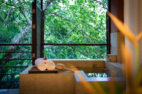 une salle de bain avec une baignoire avec une fenêtre et une serviette dans l'établissement Narada Resort & Spa Qixian Mount, à Baoting
