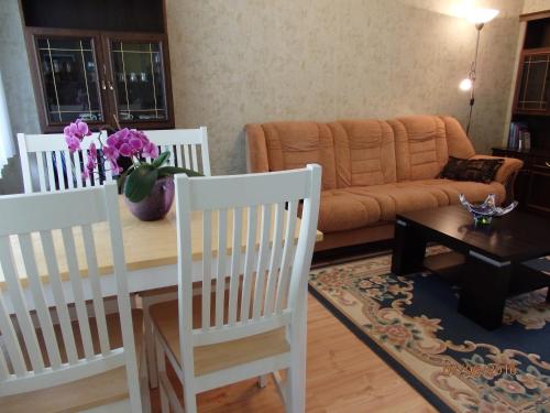 a living room with white chairs and a table with flowers on it at Torni Apartment in Kuressaare