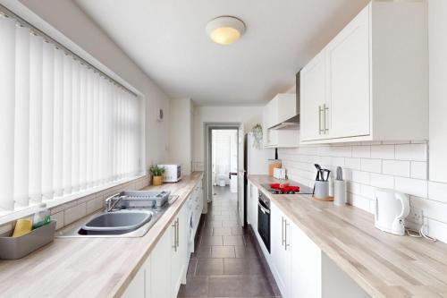 a kitchen with white cabinets and a sink at Sunderland Cosy Cottage in Sunderland
