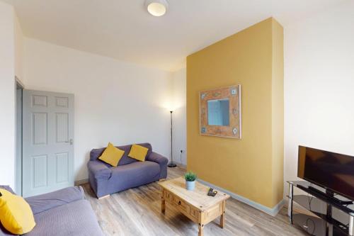 a living room with a purple couch and a tv at Sunderland Cosy Cottage in Sunderland