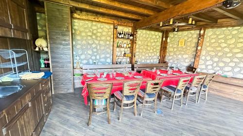 a dining room with a red table and chairs at Къща за Гости Тодор in Shiroki Dol