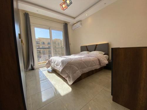 Un dormitorio con una cama y una ventana grande. en Alrehab Cheapest and awesome, en Burg el-Ḥudûd