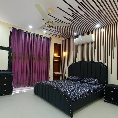 a bedroom with a black bed and purple curtains at Modern Villa DHA in Lahore